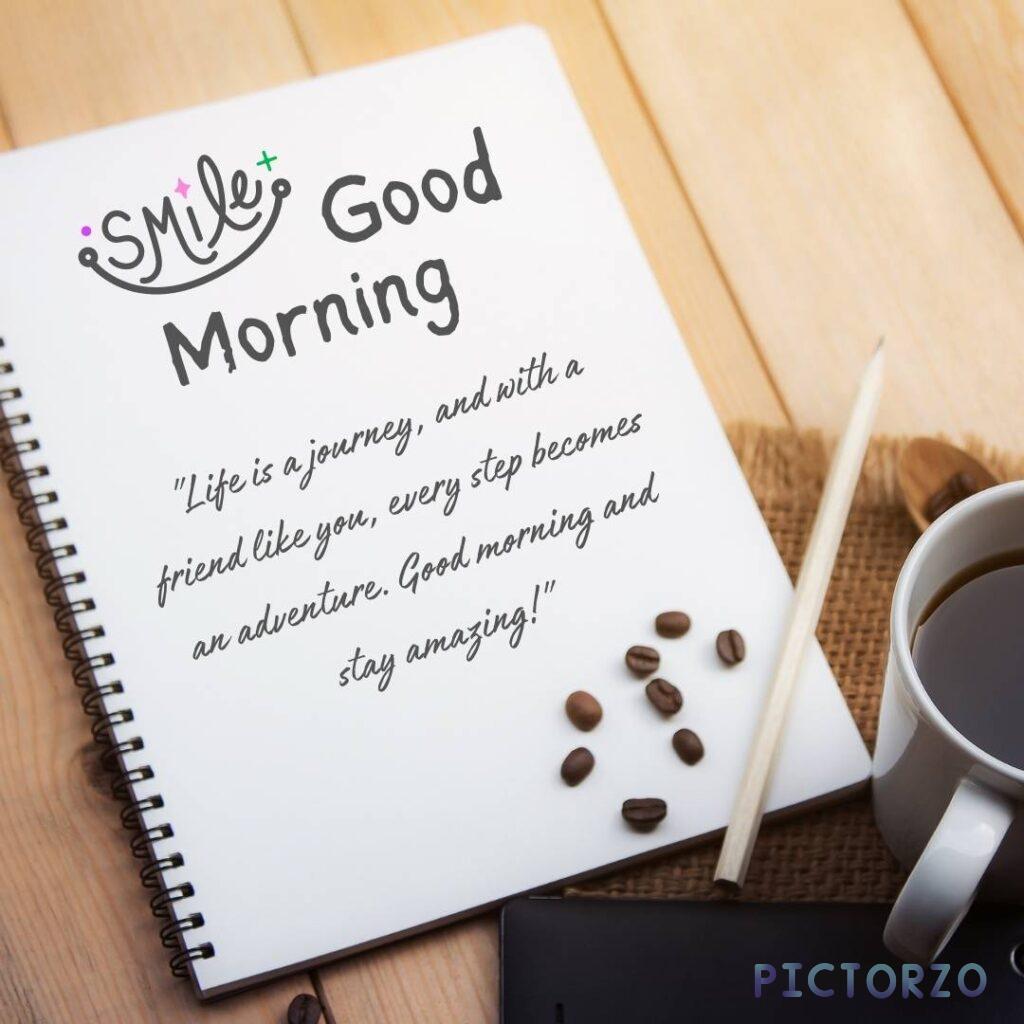 A notebook with a quote on it that says: "Life is a journey, and with a friend like you, every step becomes an adventure. Good morning and stay amazing!" The notebook is sitting on a wooden desk, and there is a cup of coffee next to it
