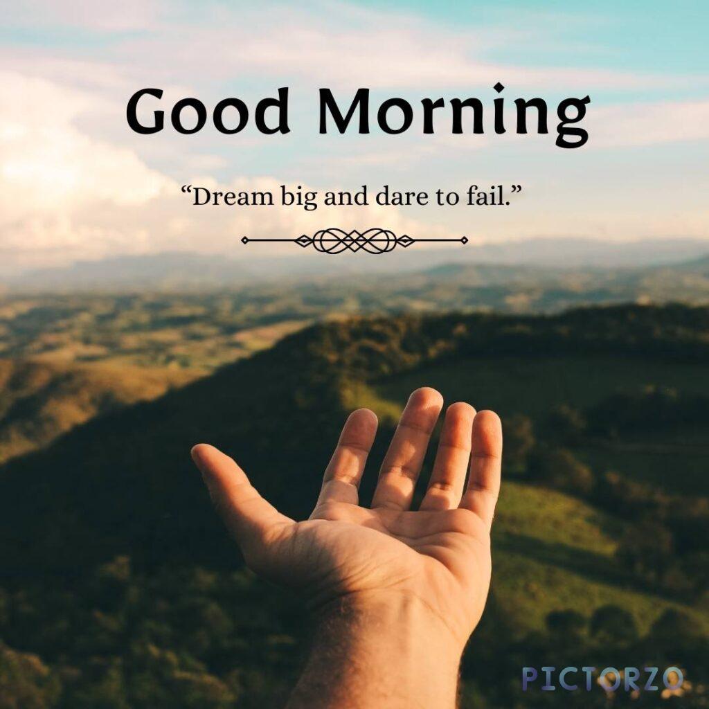 A photo of a hand reaching up to the sky, with the text Good Morning overlaid on it. The background is a beautiful nature scene, with trees, mountains