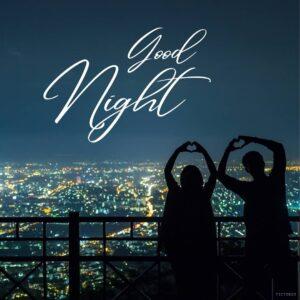 A couple making a heart shape with their hands at night with the text Good Night between them