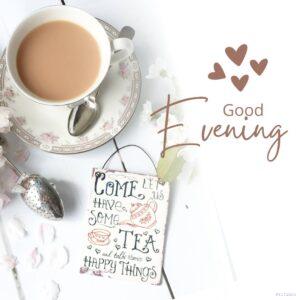 Good Evening Tea and Coffee Images 11 A cup of tea sitting on top of a saucer, with the text "Good evening! Come have some tea and talk about happy things" above it. The teacup is on a wooden table in front of a retro metal hanging sign that says "Sass Belle Retro Come Lets Have Some Tea