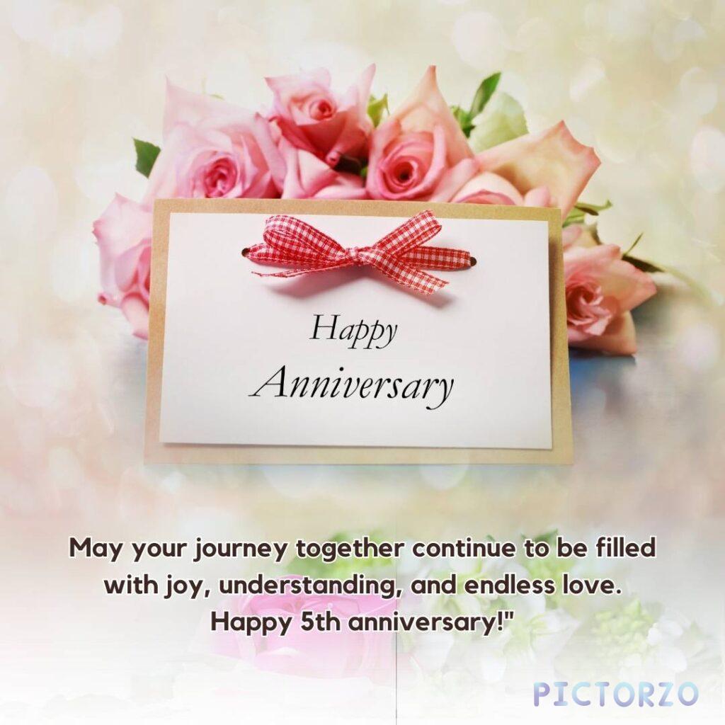 A pink anniversary card with a border of pink roses. The card has the text "Happy Anniversary" written in a decorative font at the top. Below the text is a message that reads: "May your journey together continue to be filled with joy, understanding, and endless love. Happy 5th Anniversary!
