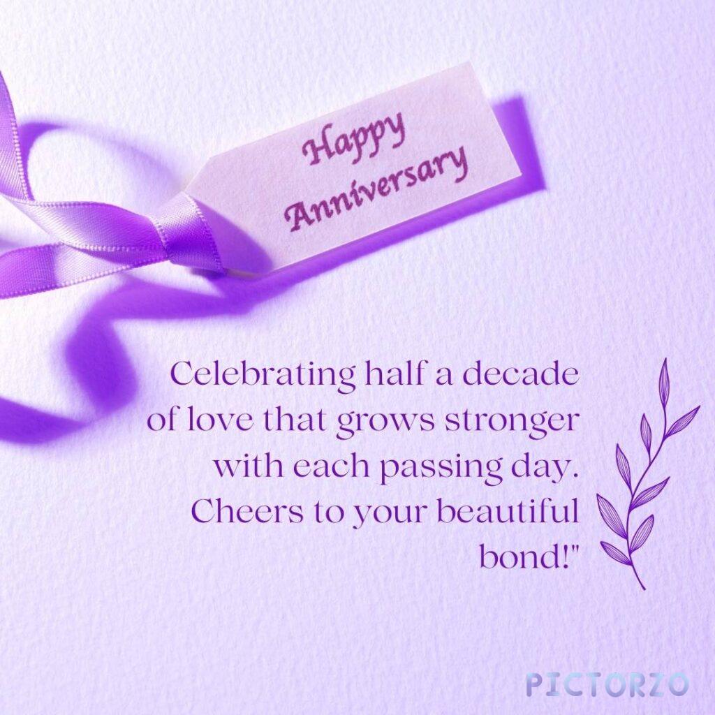 A purple anniversary card with a purple ribbon. The card has the text "Happy Anniversary" written in gold foil at the top. Below the text is a message that reads: "Celebrating half a decade of love that grows stronger with each passing day. Cheers to your beautiful bond!