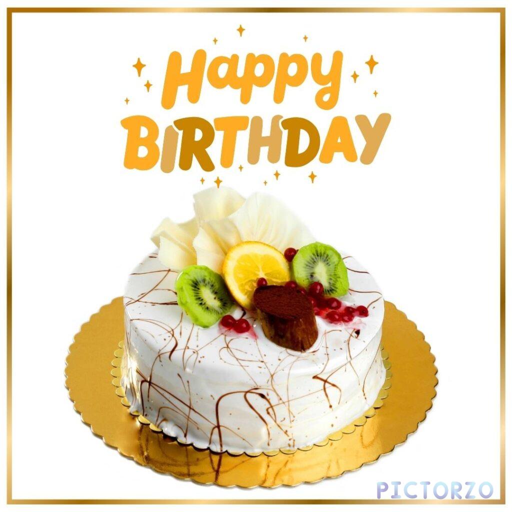 Close-up of a delicious-looking round birthday cake with a white chocolate exterior, decorated with chocolate sprinkles and fresh fruit, including orange, kiwi, and raspberries. The cake has a gold ribbon tied around it and a gold "Happy Birthday!" banner on top.