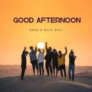 many friends are standing on the desert mountain clicking cool photos in front of the camera with the sun sitting in the background and text is good afternoon have a nice day on it